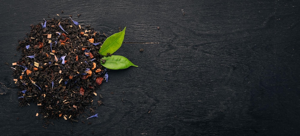  Black tea with flower petals of cornflower and dry berries on a wooden background top view copy spa