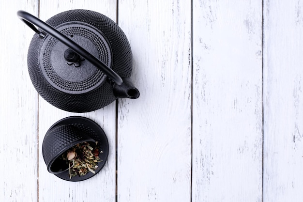 Black teapot bowl and tea on color wooden background