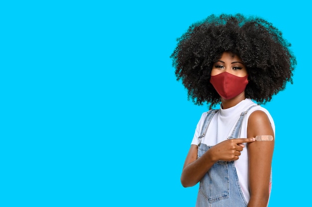 Photo black teen girl wearing face shield points to the vaccine sticker on the square you can see the smil