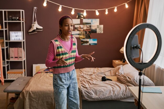 Photo black teenage girl recording video for social media with ring light