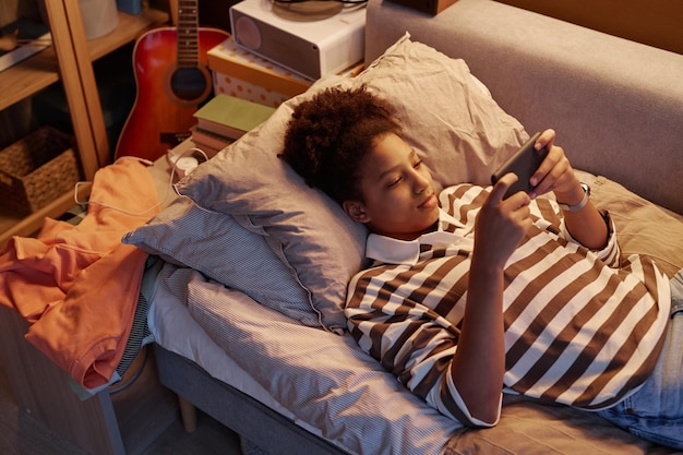 Black teenage girl using smartphone and playing games