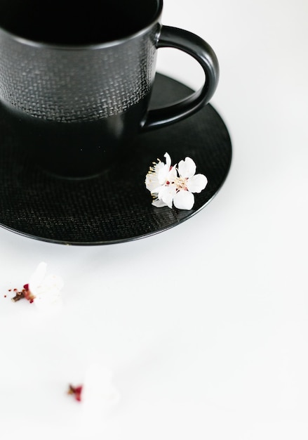 비문에 대 한 꽃이 만발한 봄 체리 빈 배경과 접시에 검은 질감 컵