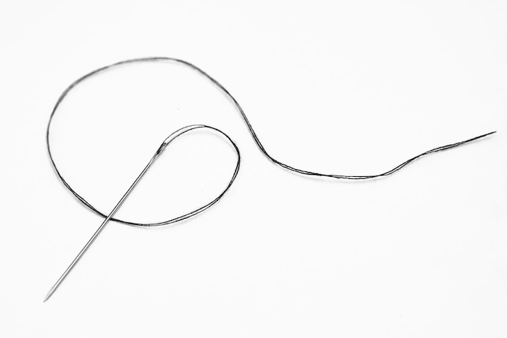 Photo black thread and needle over white background