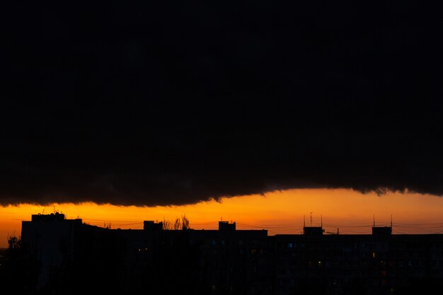 Black thunderclouds at sunset. Bright orange sunset and dark clouds. Storm sky