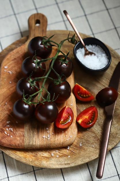 Black tomatoes with sea salt on a wooden board
