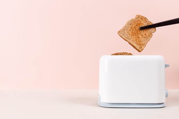 Black tongs take out the bread out of the white toaster Levitation food