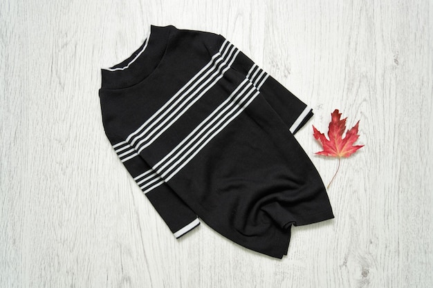 Black top in stripes on a wooden background. Maple leaf. Fashionable concept