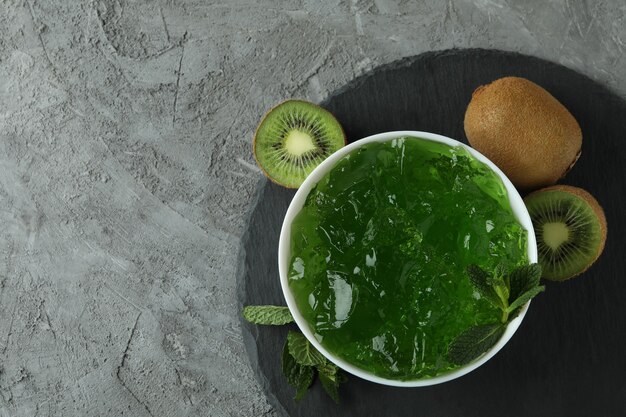 Black tray with bowl of kiwi jelly on gray textured table