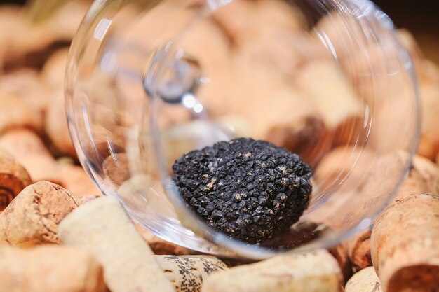 Tartufo nero in un bicchiere vuoto su tappi per vino.