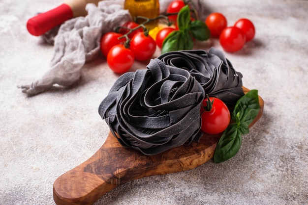 Black uncooked pasta with tomato and basil