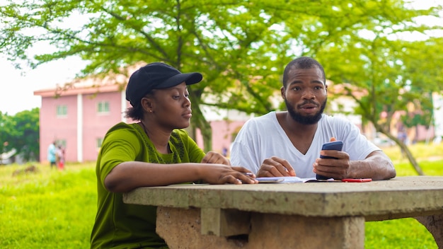 Black university handsome man assisting his female friend with\
her lecture in the campus. focus is on student.