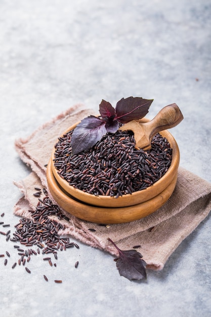 Black unpolished rice in wooden bowl. long grain rice
background.