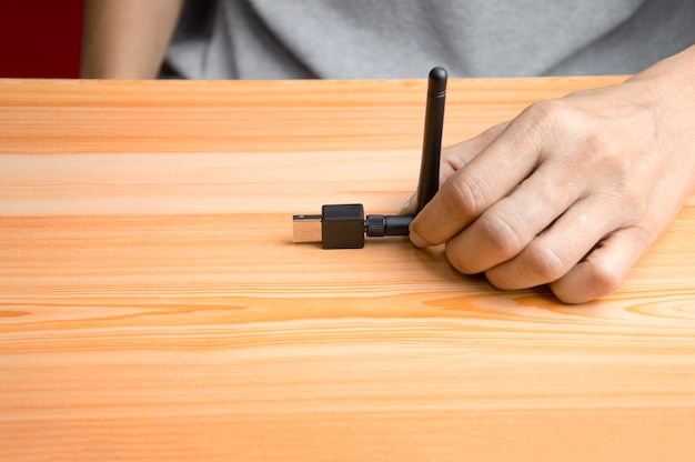 Black usb wifi placed on wooden floor hand holding usb wifi