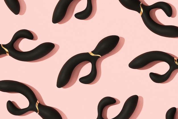 Black vibrator on the peach pink background sex toys for adults pattern