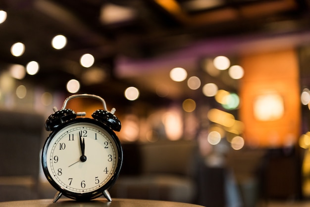 black vintage alarm clock with blurred colorful light background