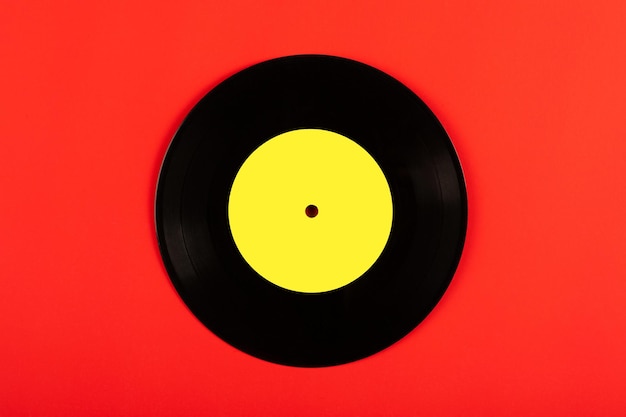 Black vinyl record with yellow label on red backgroundTop view