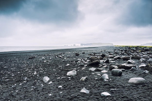 Black volcanic sand and stones on the Reynisfjara beach. Coast of the Atlantic ocean, South Iceland
