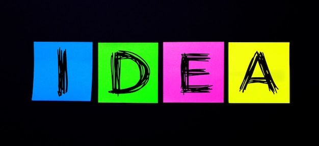 On a black wall, bright multicolored stickers with the word IDEA
