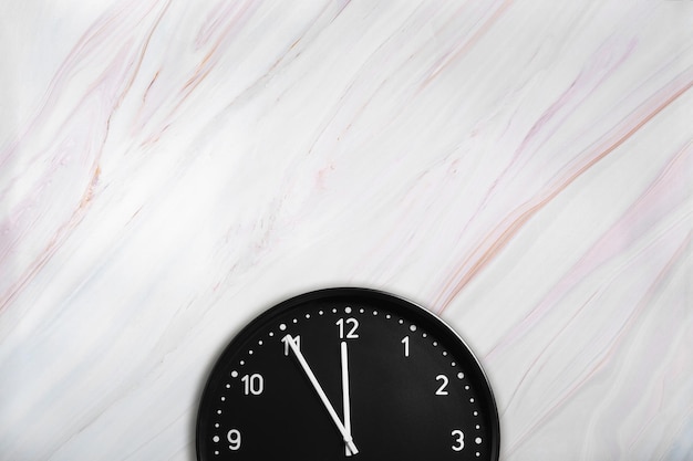 Black wall clock on marble texture with natural pattern Office clock on marble background