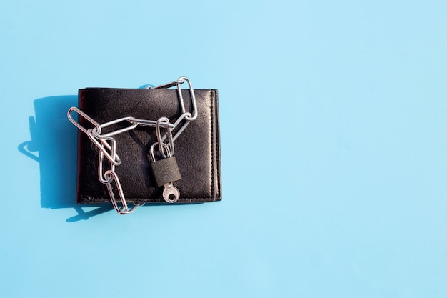 Black wallet in chains closed padlock on blue surface