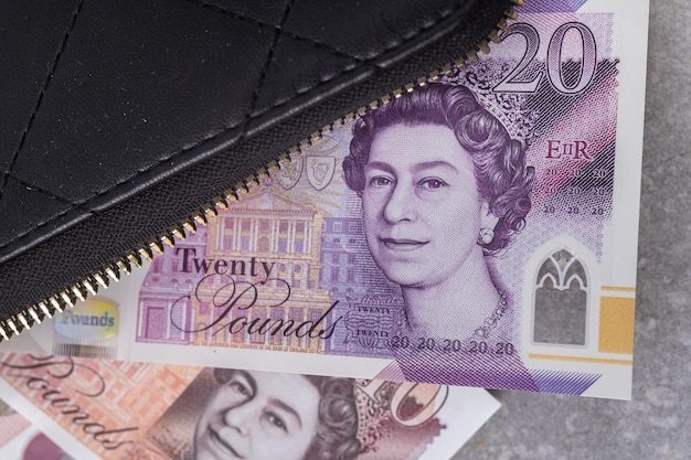 Black wallet on a gray background with 10 and 20 pound notes