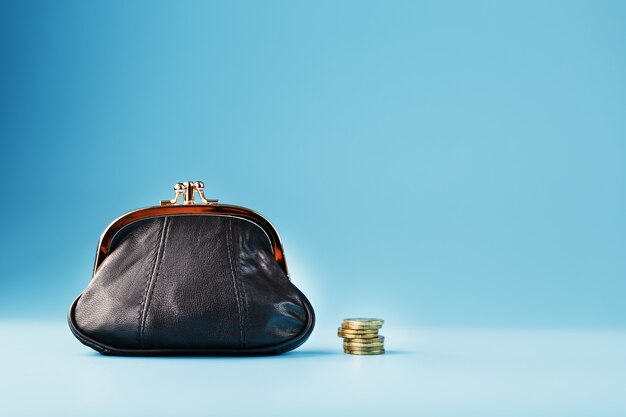 Foto portafoglio nero con monete sul blu. budget per investimenti in futuro.