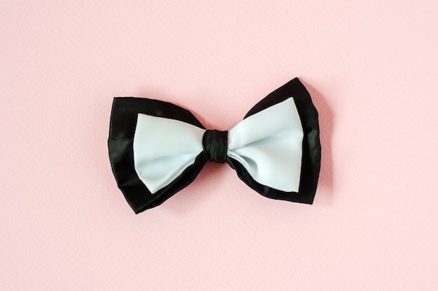 Black and white bow tie on light pink background