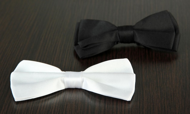 Black and white bow ties on wooden background