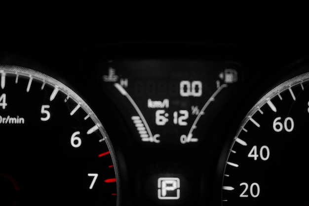 A black and white car's dashboard shows the time of 6 : 12.