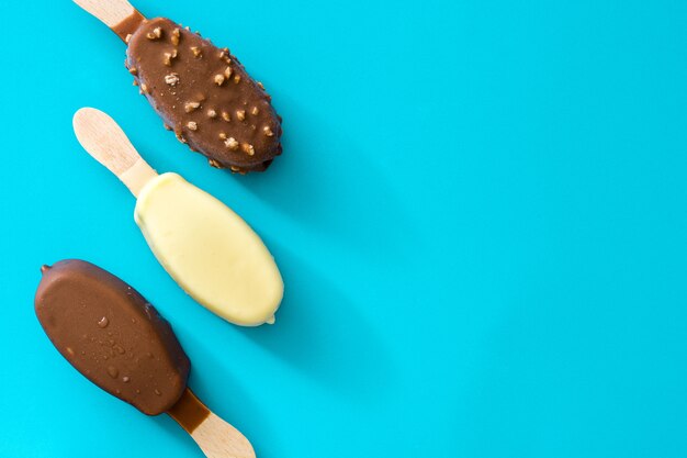 Black and white chocolate ice cream popsicles on blue top view