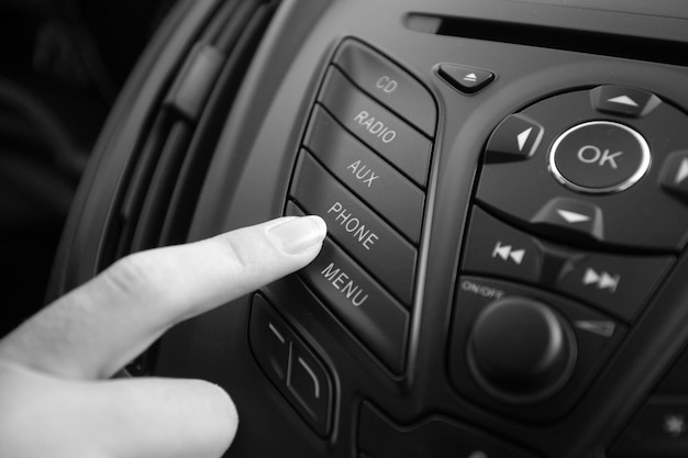 Photo black and white closeup photo of woman adjusting car stereo system