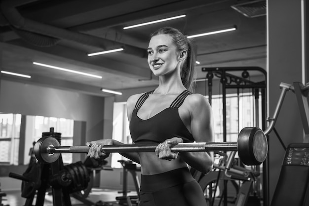 Black and white image of an athletic young woman in the gym. Bodybuilding and fitness concept. Sports and motivation. Mixed media