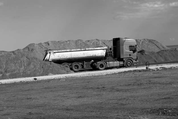 Black and white image of old truck near sand pile at the road construction site. big old roadworking tipper climbing up construction concept