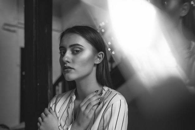 Black and white indoor portrait of a sad pretty woman wears stylish outfit. Space for text