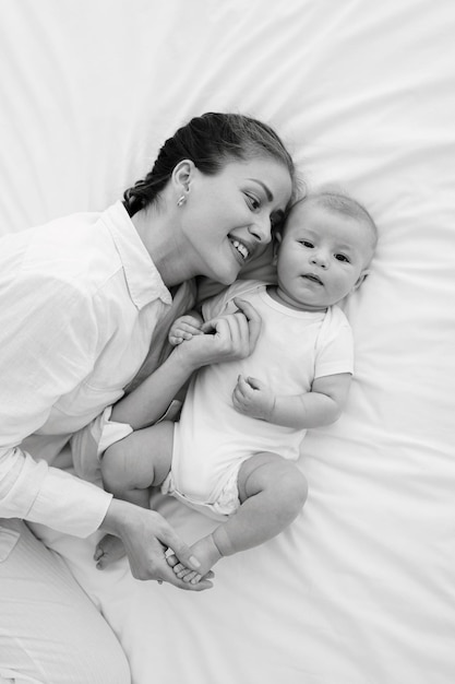 Foto ritratto di madre e figlio in bianco e nero che giocano, si baciano, si abbracciano e tengono in braccio un bambino di tre mesi