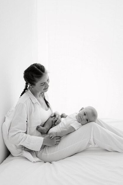 Foto ritratto di madre e figlio in bianco e nero che giocano, si baciano, si abbracciano e tengono in braccio un bambino di tre mesi