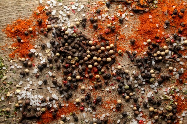 Black and white pepper peas sea salt red pepper powder cloves spices on a wooden background