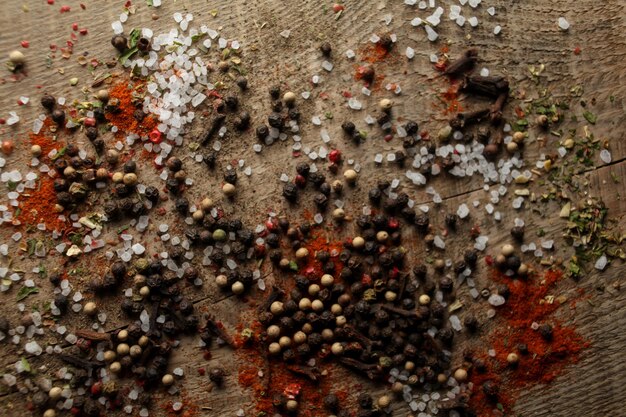 Black and white pepper peas sea salt red pepper powder cloves spices on a wooden background