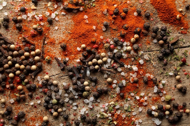 Black and white pepper peas sea salt red pepper powder cloves spices on a wooden background