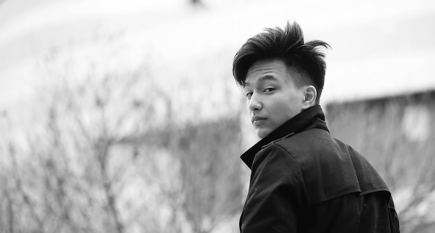 Black White photo of Asian young man outdoors posing at camera