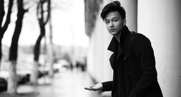 야외에서 카메라에 포즈를 취하는 아시아 젊은이의 흑백 사진