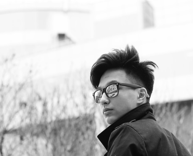 Black White photo of Asian young man outdoors posing at camera