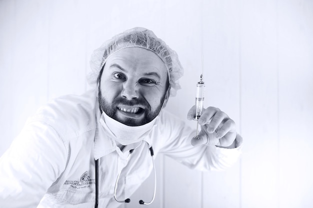 Black and white photo of  bearded doctor in a white coat and an old syringe