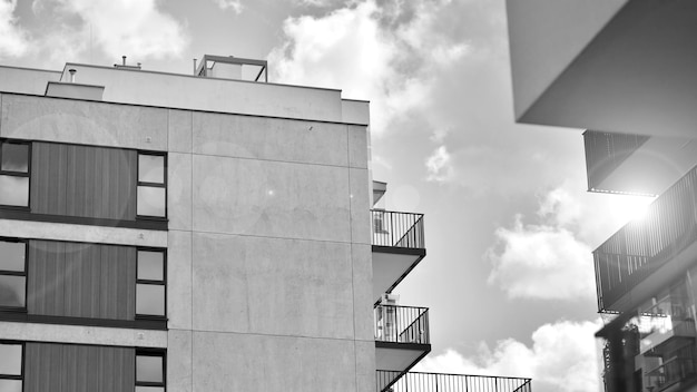 a black and white photo of a building with a balcony and a sky with clouds