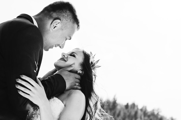 Black and white photo of cheerful emotional newlyweds who hug each other