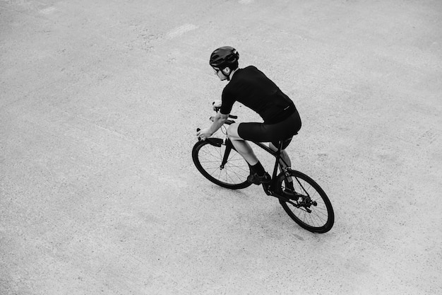 Black and white photo of man riding bike outdoors