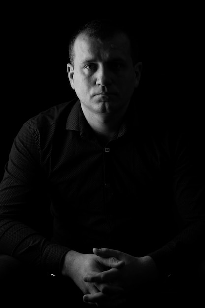 Black and white photo of a man in a shirt on a black background