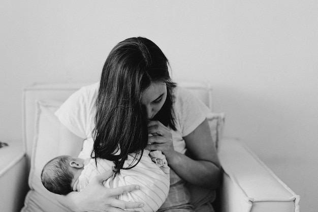 Black and white photo. Newborn baby boy sucking milk from mothers breast. Portrait of mom and breastfeeding baby. Concept of healthy and natural baby breastfeeding nutrition.