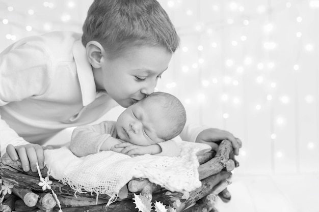 black and white photo older brother lies, hugs, hugs and holds the hand of his newborn younger broth