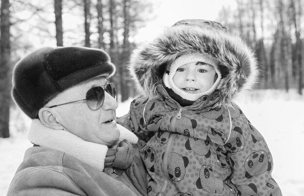 Черно-белое фото родителей, держащих ребенка на руках в зимнем парке